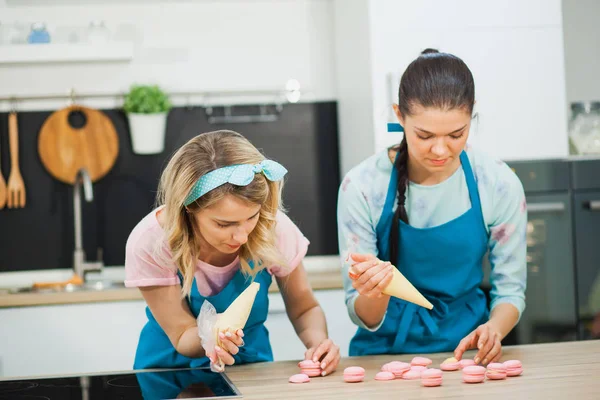 İki genç kız macaroons boru çanta ile dekorasyon dolu