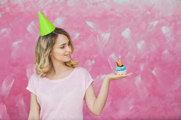 Menina loira bonita em tampão de aniversário segurar cupcake com vela — Fotografia de Stock