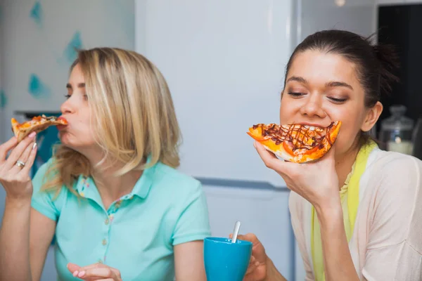 Two young women eat pizza. Girls taste italian traditional food