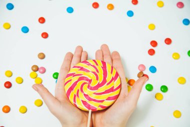 Çikolatalı şeker lolipop el beyaz arka plan yatıyordu düz