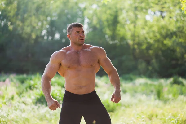Ung passar topless bodybuilder utomhus visar musklerna — Stockfoto