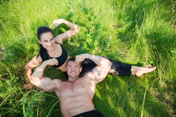Par av unga idrottsmän ligga på grönt gräs efter träning utomhus — Stockfoto