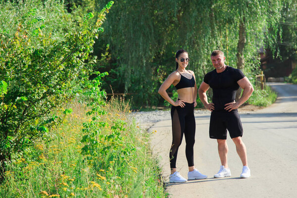 Couple of strong fit man and woman in sport outdoors ready for workout with earphones on a sunny day