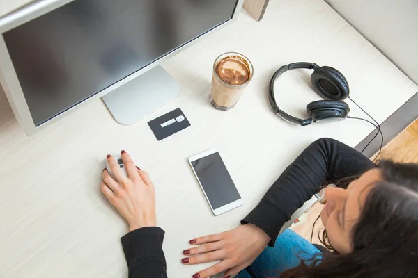 Молодая женщина с кредитной картой и смартфоном сидеть на мониторе компьютера — стоковое фото