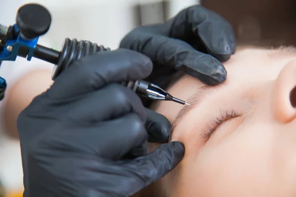 Cosmetólogo aplicando maquillaje permanente en las cejas —  Fotos de Stock
