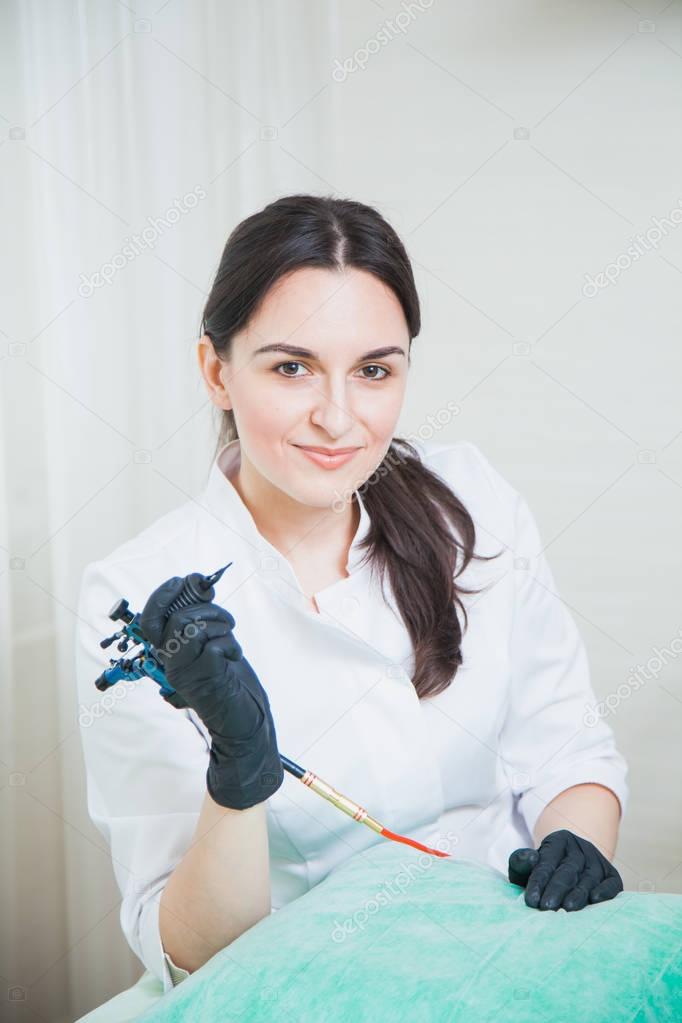 Female cosmetologist with tattoo machine
