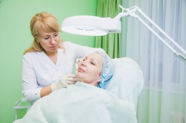 Güzellik uzmanı Şevval Özçelik Güzellik yüzüne enjeksiyon yapma. Cilt yaşlanma, gençleştirme ve hidrasyon prosedürleri. Eski üst düzey kadın güzellik salonda yüz enjeksiyonları alır. Estetik kozmetik. Yakın çekim.