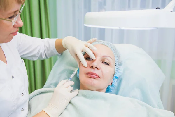 Косметолог-косметолог делает укол пожилой женщине — стоковое фото
