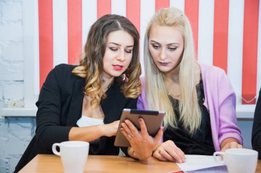 İki güzel kadın projeyi dijital tablet üzerinde tartışmak. Serbest için çalışma yerde genç kadınlarla tanışmak.