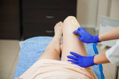 Genç kadın güzellik salonunda sugaring saç çıkarma işlemini yapma. Şevval Özçelik Güzellik Güzellik Uzmanı olun epilasyon sıvı şeker yapıştırın. Yakın çekim kadın bacakları