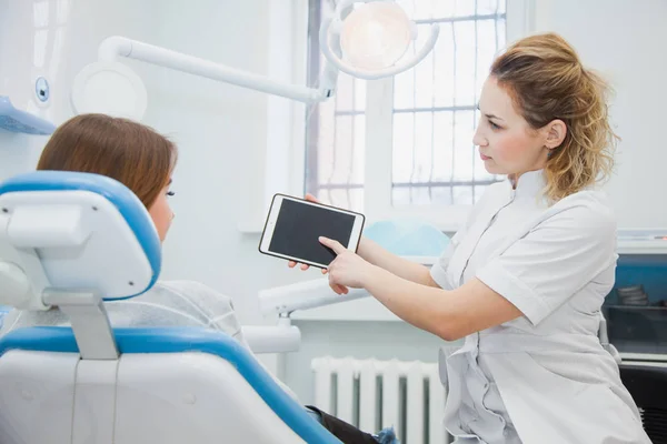 Dentista y paciente discutiendo tratamientos en una aplicación de tableta . —  Fotos de Stock