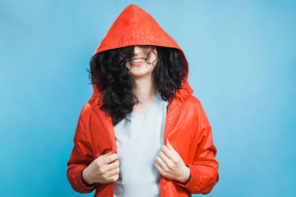 Happy pretty young girl in red coat hood with dark curly hair and open smile. — Stock Photo, Image