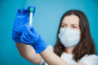 Mavi arka planda boş kan testi tüpü olan tıp öğrencisi..