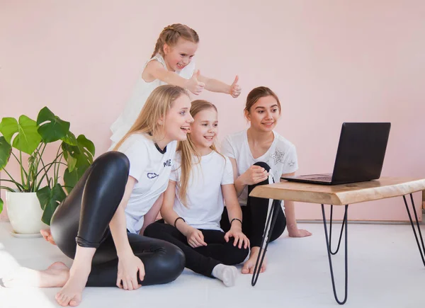 Cuatro hermanas jóvenes sonríen y miran el monitor del portátil . — Foto de Stock