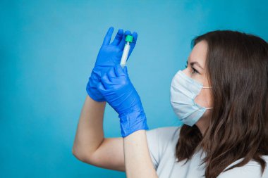 Mavi arka planda boş kan testi tüpü olan tıp öğrencisi..