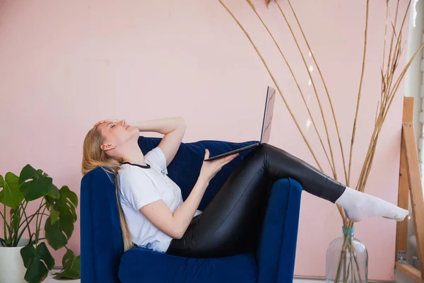 Молодая женщина в кресле держать ноутбук и работу из дома . — стоковое фото
