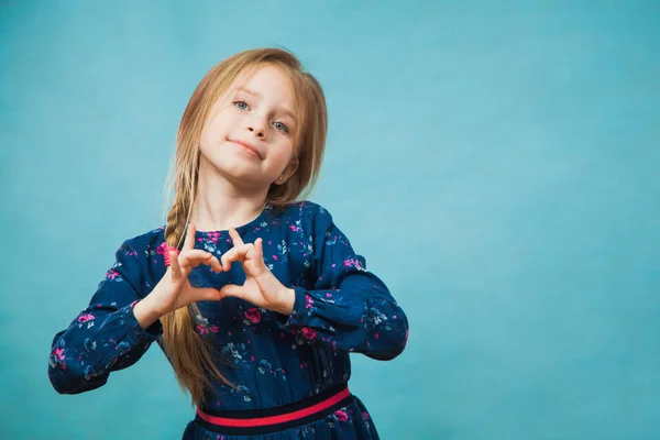 Šťastná potěšená dívka v ležérní klasické modré šaty úsměv ruce ve tvaru srdce. — Stock fotografie