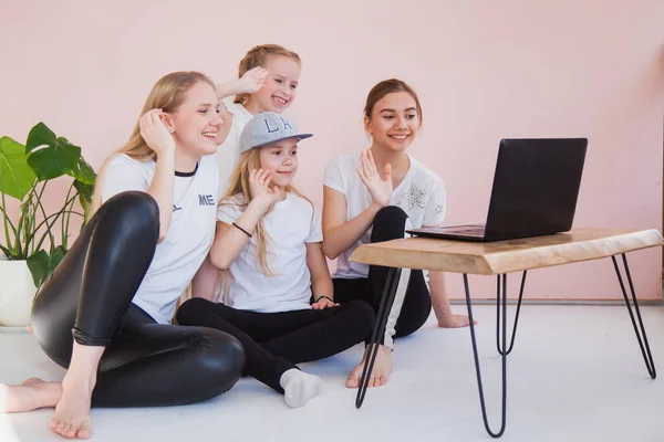 Vier junge Schwestern lächeln und blicken auf den Monitor ihres Laptops. — Stockfoto