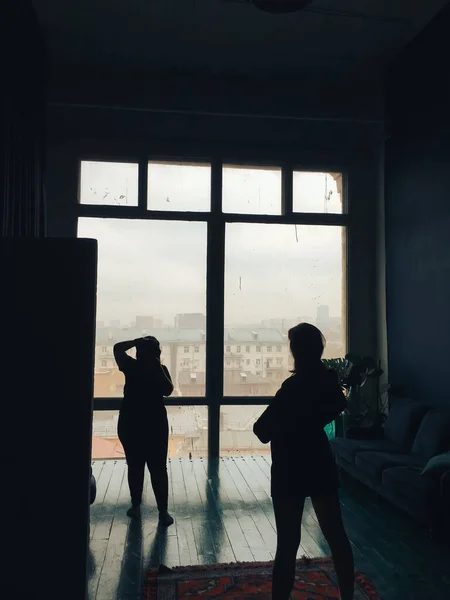 silhouette of the photographer and model in the studio on the background of huge windows 1