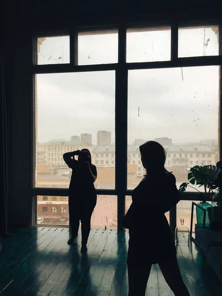 silhouette of the photographer and model in the studio on the background of huge windows 1