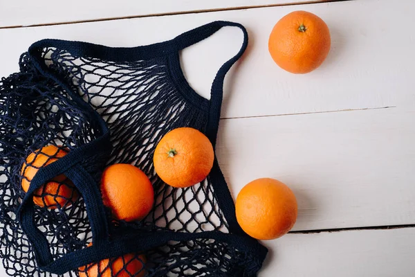 eco- friendly bag string bag with oranges on a wooden background