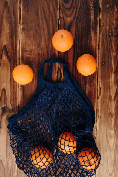 eco- friendly bag string bag with oranges on a wooden background