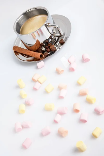 Marshmallows multicoloridos em um fundo branco. Atrás deles está uma xícara de café com grãos e canela . — Fotografia de Stock