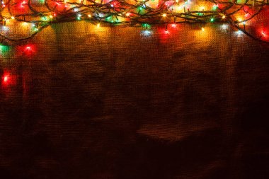 Çuval bezi karanlıkta arka planda parlak Noel çelenk.