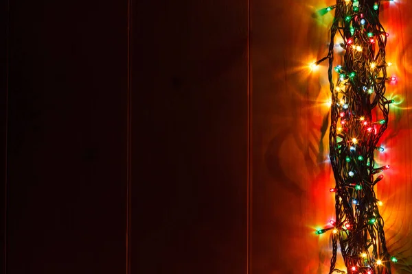 Glödande Christmas garland på trä bakgrund i mörkret. — Stockfoto