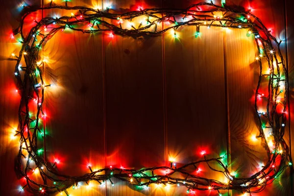 Glowing Christmas garland on the wooden background in the darkness.