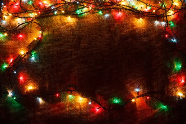 En lysande jul krans i bakgrunden av säckväv i mörkret. — Stockfoto