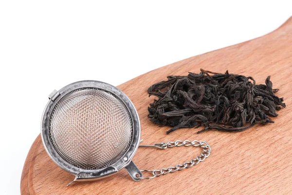 Черный чай, и ситечко с цепью, на деревянном фоне . — стоковое фото