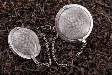Bir zincir filtresinde iki çay siyah çay kuru çay yaprakları yığını üzerinde. Bir mutfak Aksesuar bir close-up bir çay filtredir.