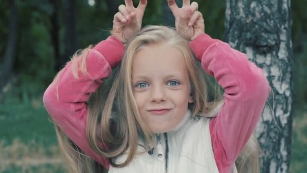 Petite fille mignonne faisant des cornes et riant dans le parc d'automne .