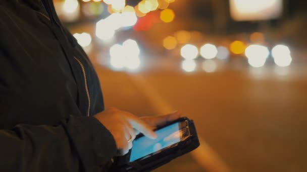 Close-up van vrouw met behulp van tablet pc buiten in de stad 's nachts, alleen handen te bezien. achtergrond van de levensstijl. — Stockvideo