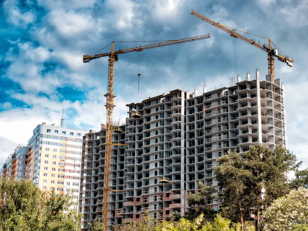 Mavi gökyüzü arka plan üzerinde bina inşaat yakınındaki iki vinç.