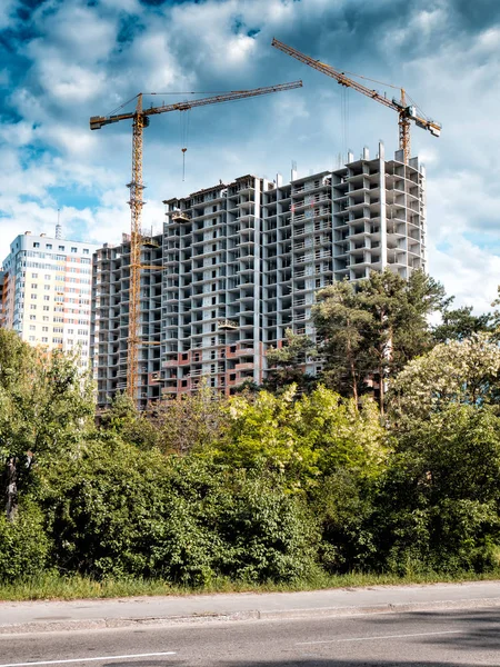 Mavi gökyüzü arka plan üzerinde bina inşaat yakınındaki iki vinç.