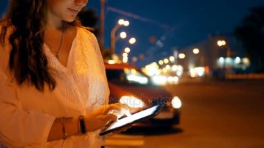 Close-Up genç kız gece şehir arka plan üzerinde tablet PC'yi kullanma.