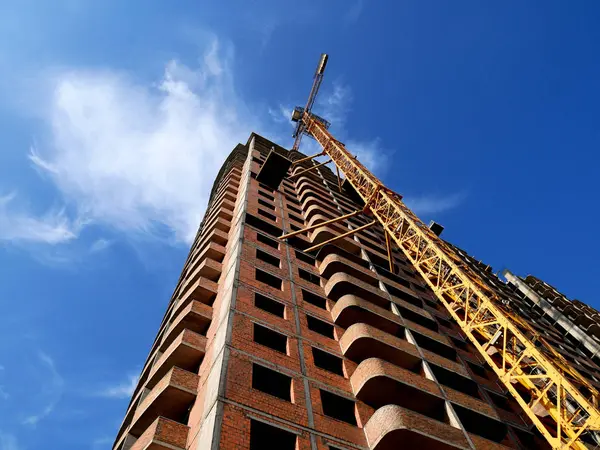 Grúa de construcción cerca de la construcción sobre fondo azul cielo . — Foto de Stock