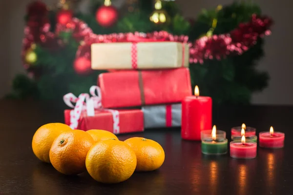Γκρο πλαν, μανταρίνια, κεριά και δώρα με το χριστουγεννιάτικο δέντρο στο φόντο — Φωτογραφία Αρχείου
