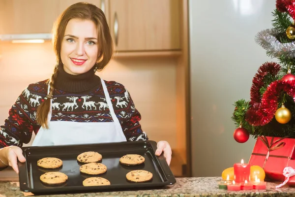 クリスマス ツリーの近くに焼きたてのチョコレート クッキーを保持若い幸せな女 — ストック写真