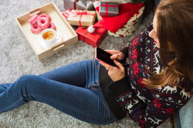 Noel'de cep telefonu ile mesaj yazarak genç gülümseyen kadın