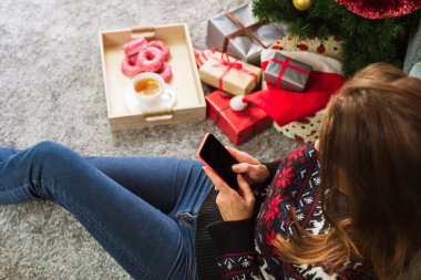 Noel'de cep telefonu ile mesaj yazarak genç gülümseyen kadın