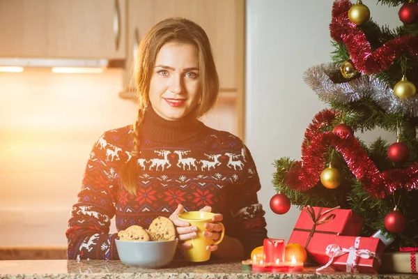 Junge glückliche Frau hält eine Tasse Tee in der Nähe des Weihnachtsbaums — Stockfoto