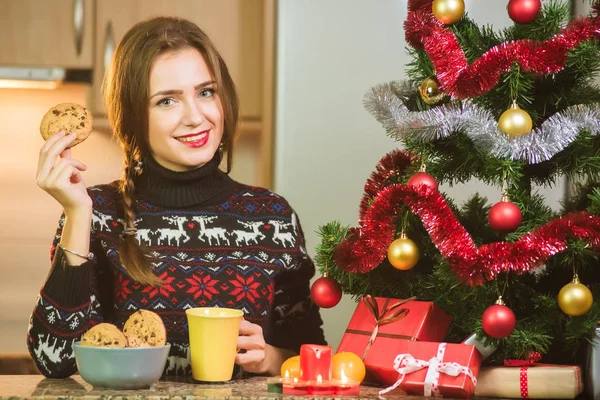Junge glückliche Frau hält Schokokekse in der Nähe des Weihnachtsbaums — Stockfoto