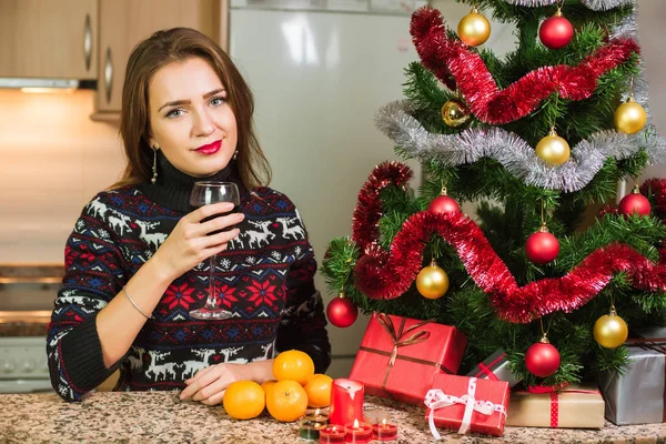 Young happy woman with glass of wine close to Christmas tree — Stock Photo, Image
