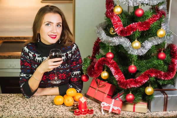 Junge glückliche Frau mit einem Glas Wein in der Nähe des Weihnachtsbaums — Stockfoto