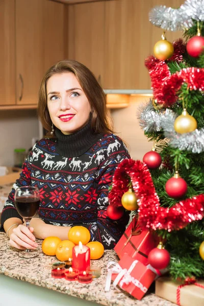 Junge glückliche Frau mit einem Glas Wein in der Nähe des Weihnachtsbaums — Stockfoto