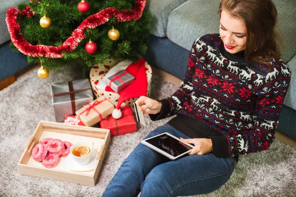 Mujer joven sosteniendo tarjeta de crédito y tableta en Navidad — Foto de Stock