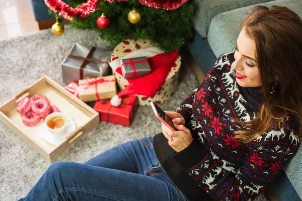 Noel'de cep telefonu ile mesaj yazarak genç gülümseyen kadın